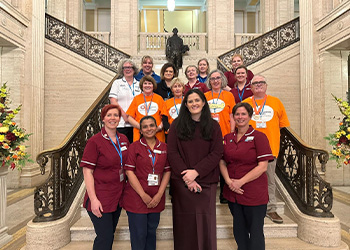 Claire Sugden MLA (Chair of All Party Group on Aging and Older People) with NI FLS nurses, ROS volunteers, Belfast Trust Community Falls Team and Radiographers on the stairs at Stormont