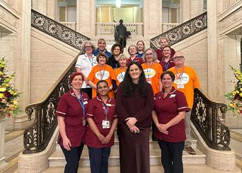 Claire Sugden MLA (Chair of All Party Group on Aging and Older People) with NI FLS nurses, ROS volunteers, Belfast Trust Community Falls Team and Radiographers on the stairs at Stormont